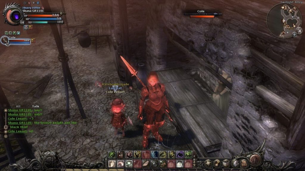 Un personnage de jeu vidéo en armure rouge se tient dans une ruelle, accompagné d'un autre personnage plus petit. L'environnement est sombre et médiéval, avec des bâtiments en pierre visibles.