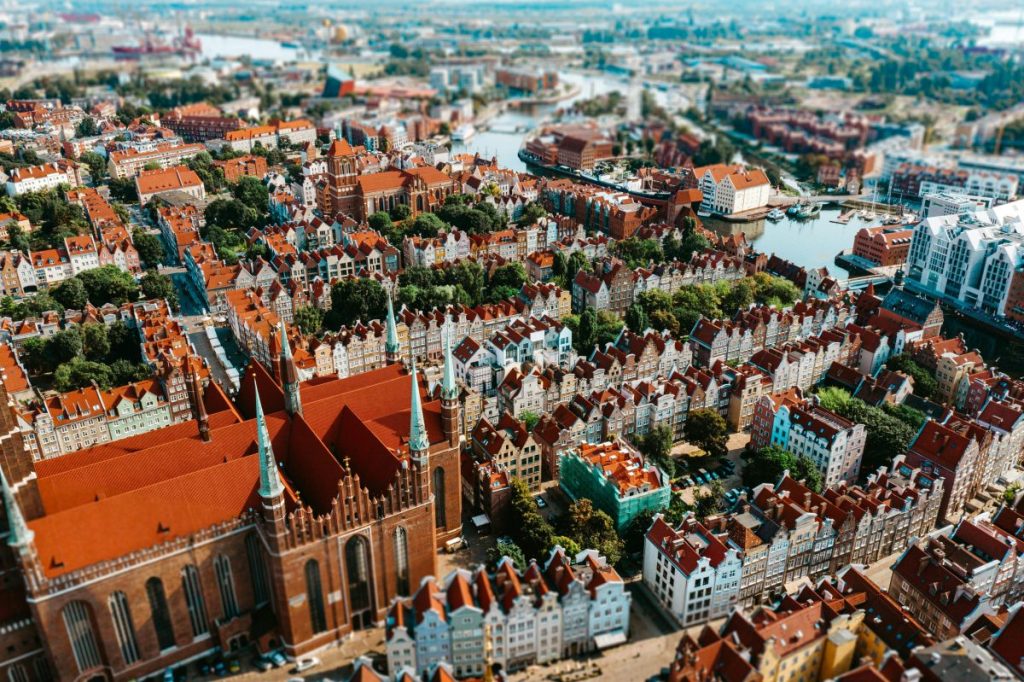 Vue aérienne de la ville de Gdansk, montrant des bâtiments historiques aux toits rouges et des canaux.