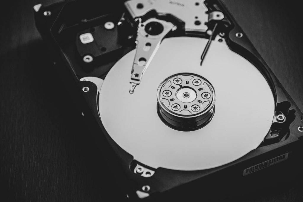 Disque dur ouvert montrant un plateau rond et un bras de lecture, en noir et blanc. Google IA et mort du web