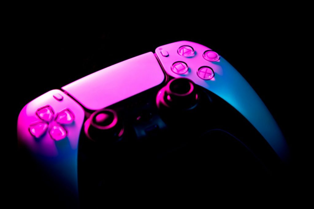 Contrôleur de jeu avec un éclairage violet et bleu sur fond noir.