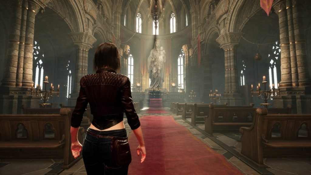 Une femme de dos se tient dans une grande église avec des voûtes gothiques, un chemin rouge qui mène à une statue centrale, entourée de bancs et de chandeliers.