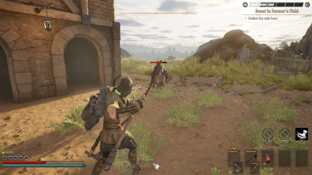 Un personnage de jeu vidéo, armé d'un arc, se prépare à attaquer un sanglier sauvage dans un champ. En arrière-plan, une construction en pierre et des rochers sont visibles.